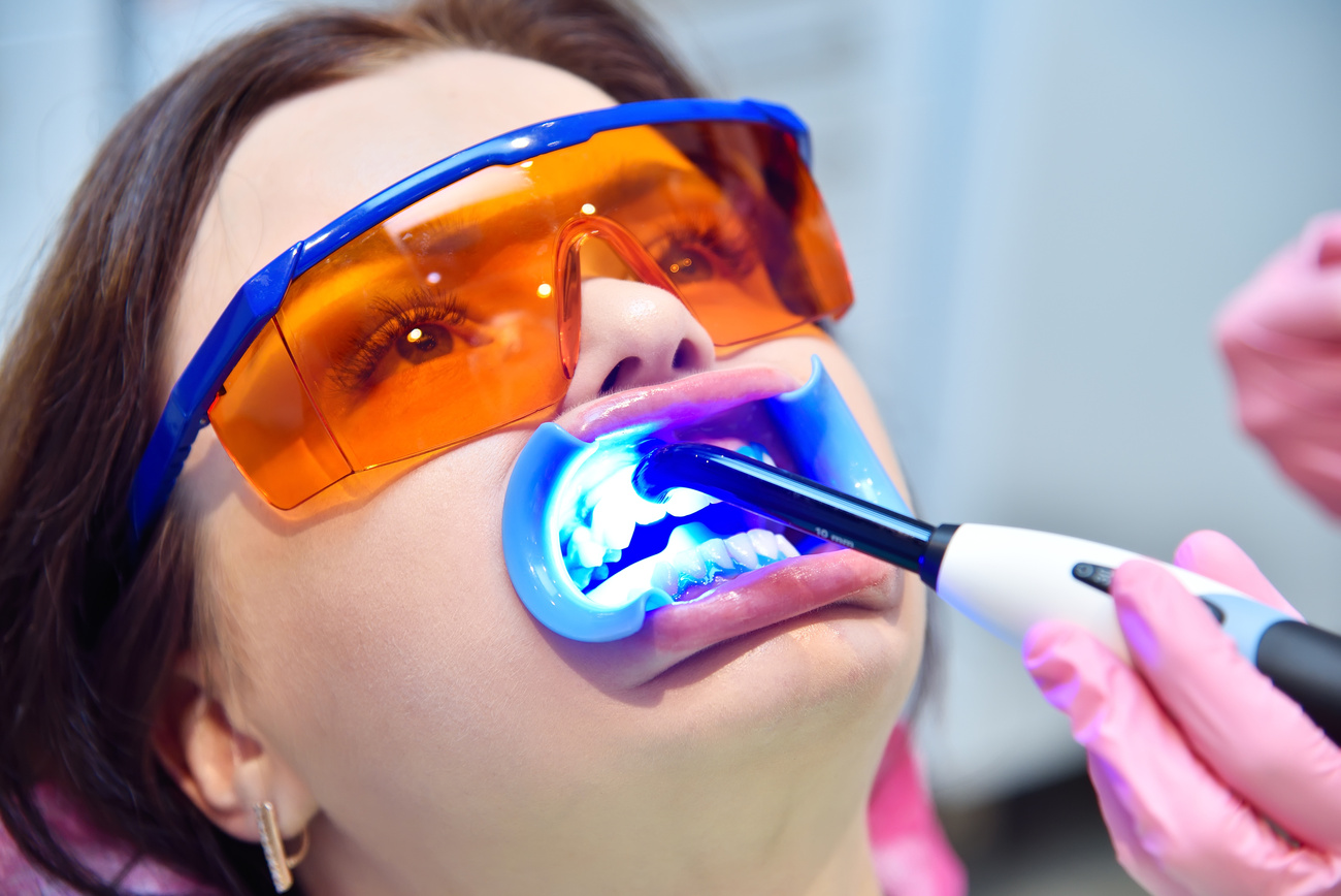 Woman Having Teeth Whitened by Dental UV Whitening Device.